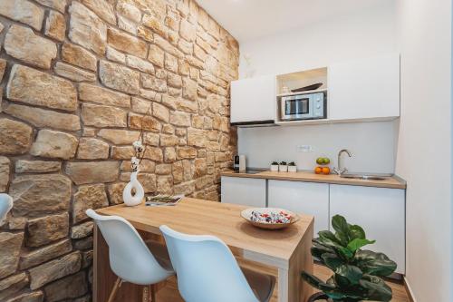 a kitchen with a wooden table and chairs and a stone wall at Four Elements - Fire & Air in Split
