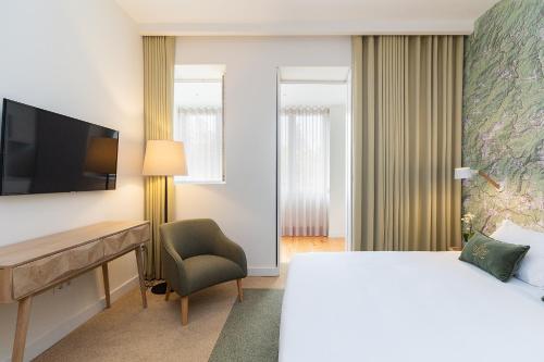 a hotel room with a bed and a desk and a television at Casa de Arouca Porto Apartments in Porto