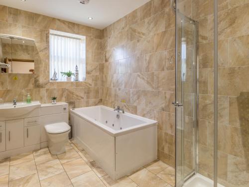 a bathroom with a tub and a toilet and a sink at Gardener's Cottage in Belford