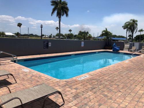a swimming pool with blue water and two chairs and palm trees at Best Western of Clewiston in Clewiston