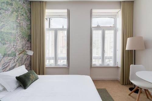 a bedroom with a bed and a table and windows at Casa de Arouca Porto Apartments in Porto
