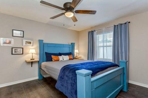 um quarto com uma cama azul e uma ventoinha de tecto em Driftwood Castle Urban Oasis with Firepit near Convention Center and Amalie Arena, Room for 6 em Tampa