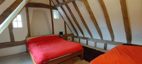 a small room with a red bed in a attic at Burnt House Cottage in Barking