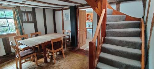 a dining room with a table and a staircase at Burnt House Cottage in Barking
