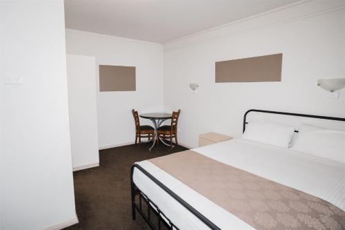 a bedroom with a bed and a table and chairs at Hurley's Bar & Bistro in Kyabram