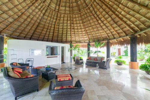 a large living room with couches and chairs and a thatch roof at Sunset Condo 104 Puerta al Mar Isla Mujeres Mexico in Isla Mujeres