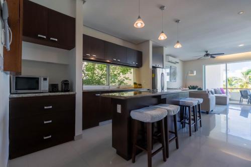 a kitchen with a large island with bar stools at Sunset Condo 104 Puerta al Mar Isla Mujeres Mexico in Isla Mujeres