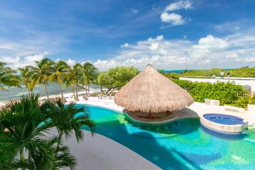a resort with a swimming pool and a straw umbrella at Sunset Condo 104 Puerta al Mar Isla Mujeres Mexico in Isla Mujeres