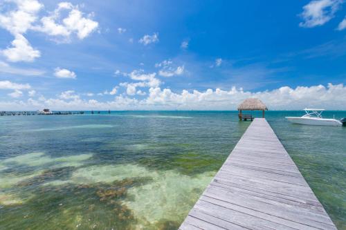 a wooden pier with a boat in the water at Sunset Condo 104 Puerta al Mar Isla Mujeres Mexico in Isla Mujeres