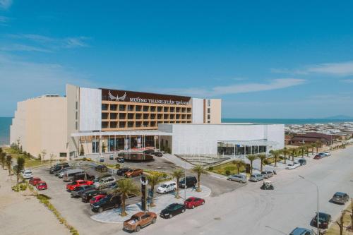 a hotel with cars parked in a parking lot at Mường Thanh Luxury Xuân Thành in Ha Tinh