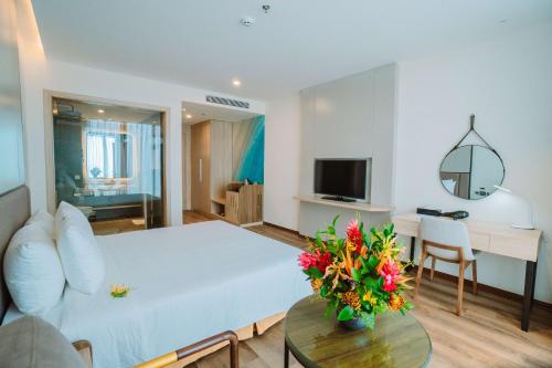 a living room with a bed and a table with flowers on it at Mường Thanh Luxury Xuân Thành in Ha Tinh