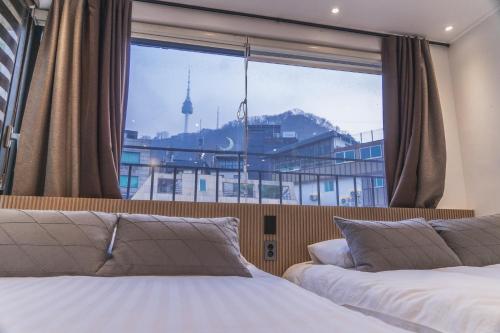 a bedroom with two beds and a large window at Myeongdong Artmonstay in Seoul