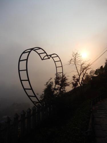 a heart shaped fence with the sunset in the background at Catcat Garden House in Sa Pa