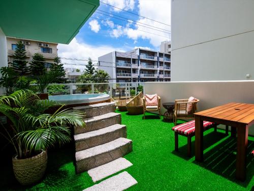 a patio with green grass and a table and chairs at The Moana by DSH Resorts in Chatan