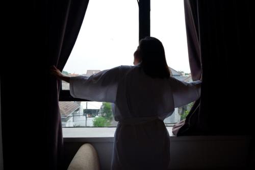 a woman is looking out of a window at News Hotel Waru Sidoarjo in Waru