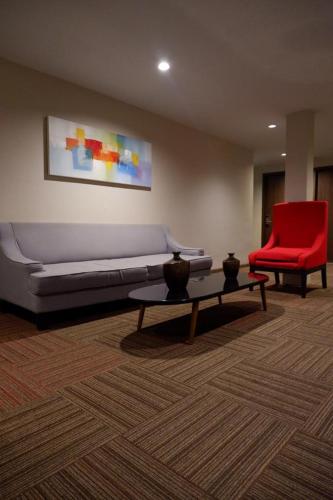 a living room with a couch and a red chair at News Hotel Waru Sidoarjo in Waru