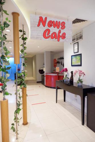 a lobby with a news cafe sign and plants at News Hotel Waru Sidoarjo in Waru