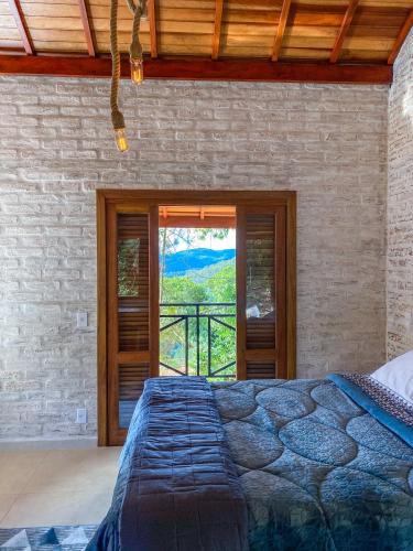 um quarto com uma cama em frente a uma janela em Refúgio Physis Suítes em Monte Verde
