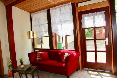 a red couch in a living room with windows at KrabatResidenz - Apartmenthaus in Burg