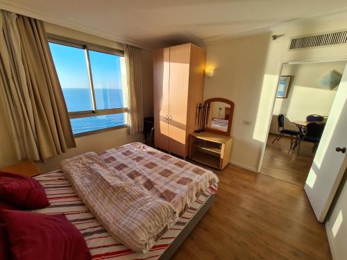 a bedroom with a bed and a large window at Haifa Beach Apartment in Haifa