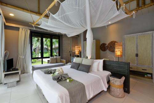 a hotel room with a bed and a canopy at Twin Lotus Resort and Spa - SHA Plus in Ko Lanta
