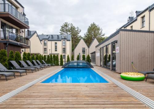 a swimming pool on a deck next to some buildings at VineWood Apartment, By Cohost in Palanga