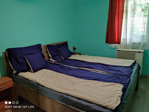a bed in a room with a blue wall at Rákóczi Vendégház in Poroszló