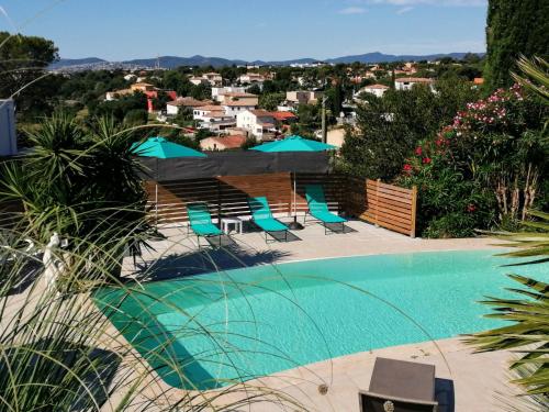 une piscine avec chaises et parasols dans l'établissement VILLAS-Piscine les MIMOSAS, à Fréjus