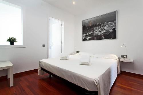 a white bedroom with a large bed and a window at MUNTANYA - Apartment with balcony Sagrada Familia in Barcelona