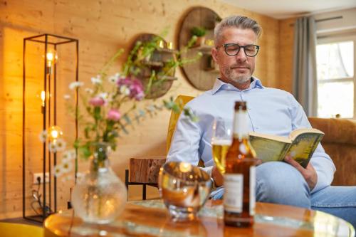 a man sitting on a couch reading a book at Parkhotel Bad Griesbach in Bad Griesbach