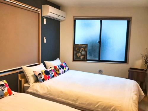a bedroom with two beds and a window at JR Tokyo family room @Otsuka Bovine 101 in Tokyo