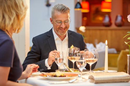 a man and a woman sitting at a table eating food at Parkhotel Bad Griesbach in Bad Griesbach