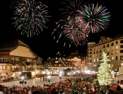 a crowd of people standing around a christmas tree with fireworks at Ascent Residence 309 in Avon