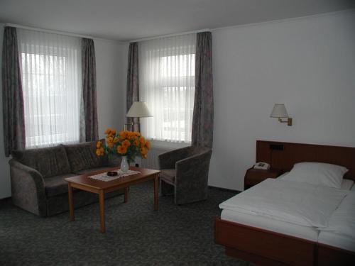 a hotel room with a bed and a couch and a table at Hotel Landhaus Greene in Einbeck