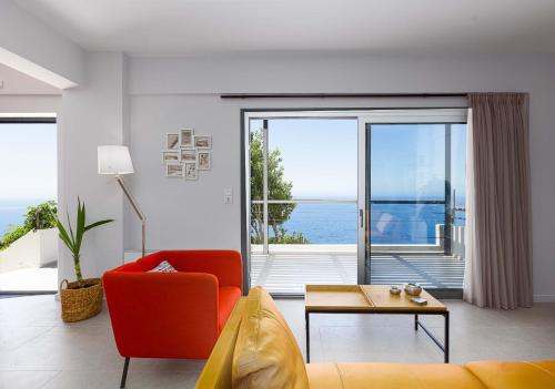 a living room with a red couch and a view of the ocean at Anemos Luxury Villas in Rodakino