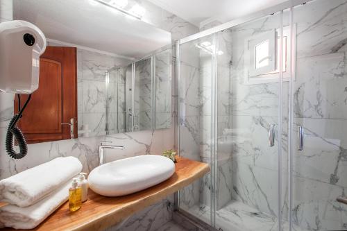een badkamer met een glazen douche en een wastafel bij Hermes Hotel in Vromolimnos