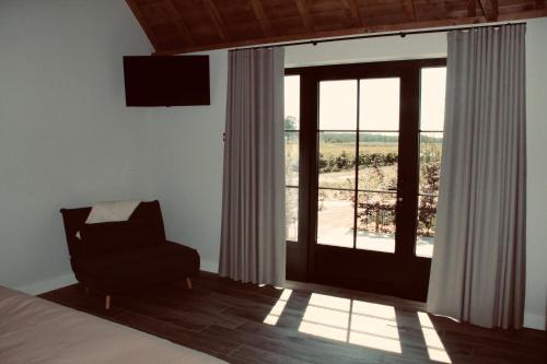 a bedroom with a bed and a chair and a window at B&B Biesvenhof in Merksplas