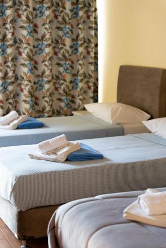 two beds in a hotel room with towels on them at Ornella Beach Resort & Villas in Sivota