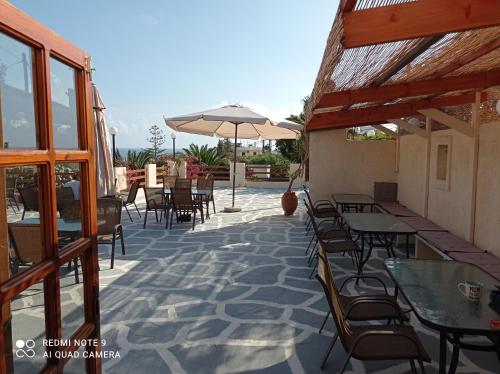 a patio with tables and chairs and an umbrella at Alexandros Studios in Kalamaki Chanion