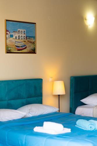 a bedroom with two beds and a painting on the wall at Ornella Beach Resort & Villas in Sivota
