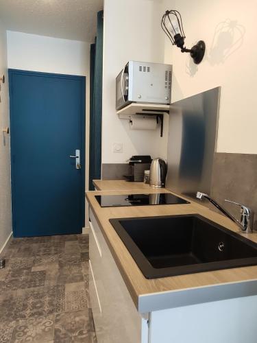 - une cuisine avec un évier et une porte bleue dans l'établissement Le Danycan - 18mn à pied gare TGV, à Saint-Malo