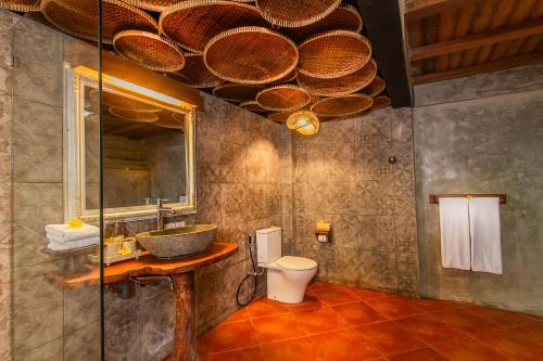 La salle de bains est pourvue d'un lavabo, de toilettes et d'un miroir. dans l'établissement Sacred Valley by Pramana Villas, à Tegalalang