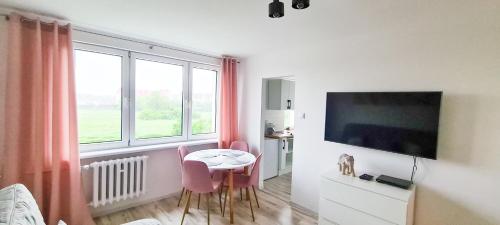 uma sala de estar com uma mesa e cadeiras e uma televisão em Apartament Rycerski em Malbork