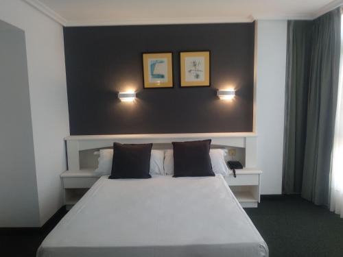una camera da letto con un grande letto con due luci sopra di HOTEL LA CAMPANA a Llanera