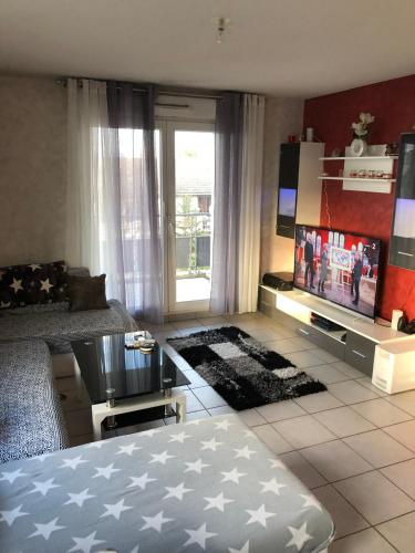 a living room with a bed and a flat screen tv at Confort d’Ange in Vaulx-en-Velin