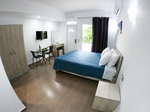 a bedroom with a blue bed and a desk and a window at Red Hibiscus Stegna in Archangelos