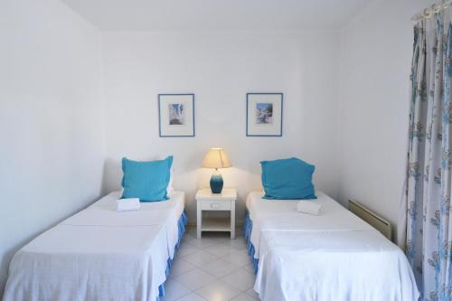 two twin beds in a room with blue pillows at Prainha Lounge in Alvor