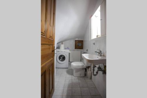 a bathroom with a toilet sink and a washing machine at Deja Blue in Mouresi