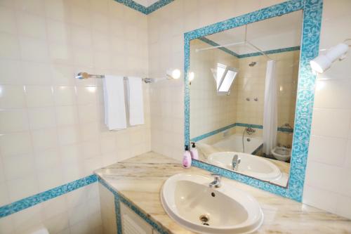 a bathroom with a sink and a mirror and a tub at Prainha Lounge in Alvor