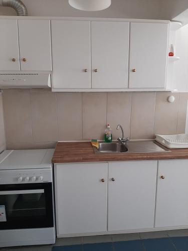 a kitchen with white cabinets and a sink at Chaniotis Studios in Kalafatis
